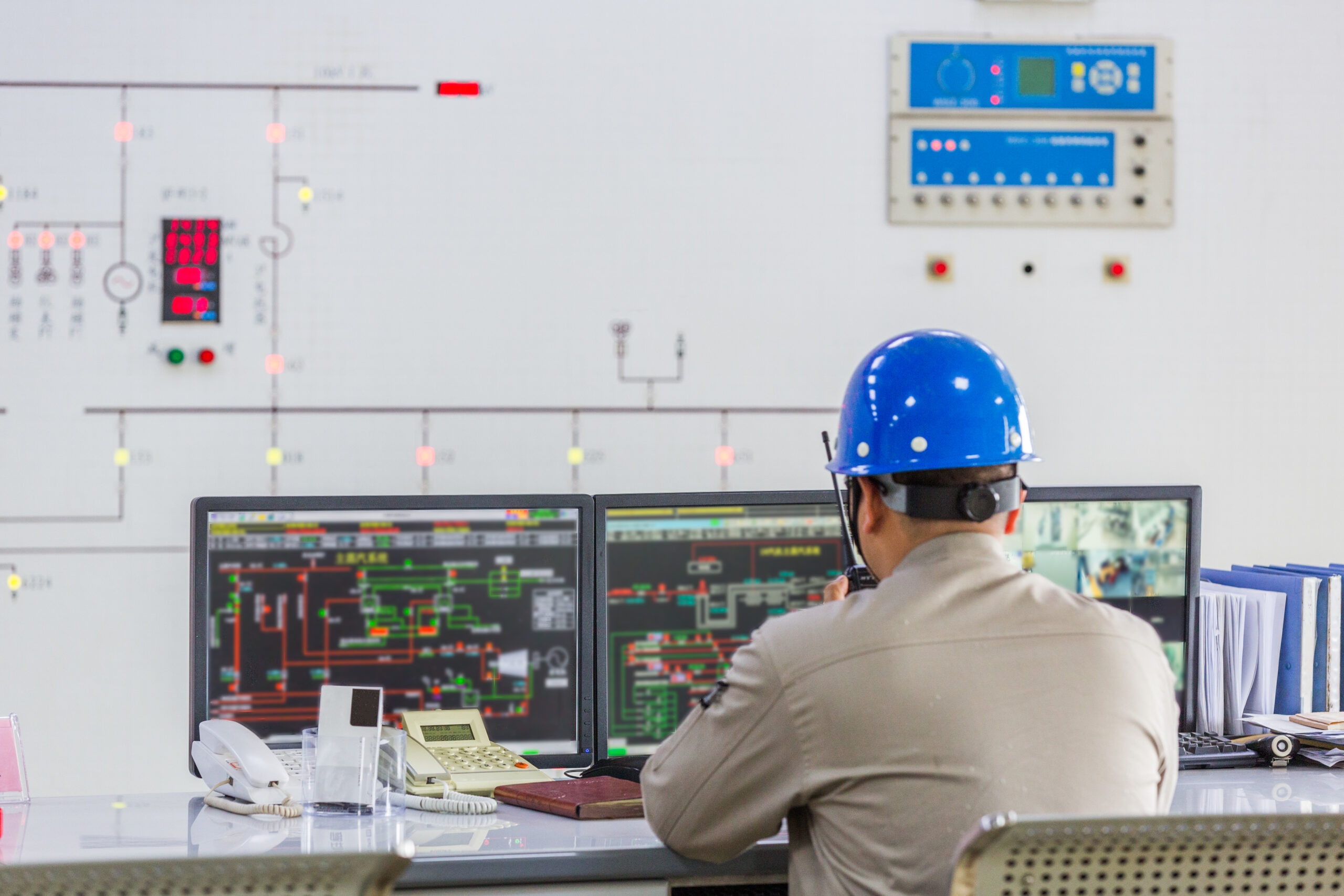 Operator monitoring automated machine data from a factory control room